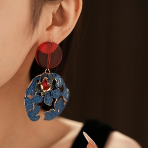 Close-up of vintage floral drop earrings with red resin and blue filigree metal
