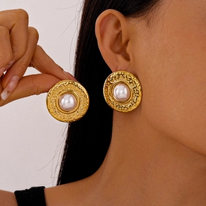 Vintage gold textured round stud earring with large white pearl on a female model