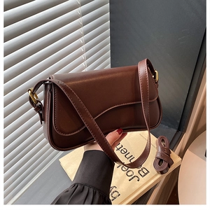 Close-up of vintage brown leather shoulder bag with metallic buckle and rich texture