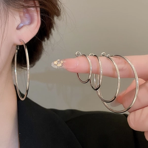 Set of four polished silver hoop earrings in varying sizes displayed on a finger