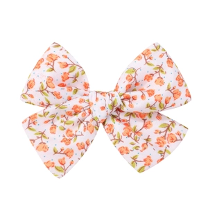 Detail of floral embroidery on fabric bow clip featuring orange flowers and green leaves