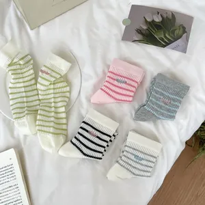 Close-up of colorful striped cotton socks set with delicate small letter embroidery detail