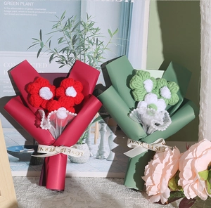 Detailed view of handmade knitted mini bouquets in red and green with floral lace wrap
