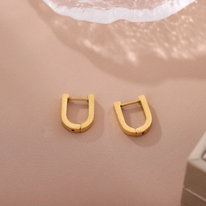 Boucles d'oreilles créoles dorées minimalistes en forme de U pour femmes sur fond beige