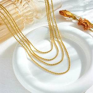 Layered gold titanium twist chain necklaces set of four on a ceramic display
