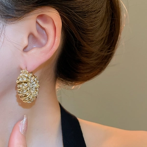 Close-up of gold U-shaped earrings with micro-pave crystals on female model