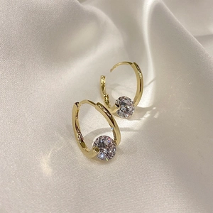 Close-up of golden tassel geometric earrings with rhinestones on white silk fabric