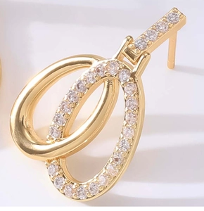 Macro shot of gold-plated double-loop earrings set with sparkling white zircon stones