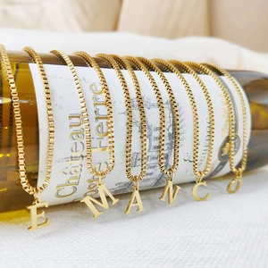 Detail of gold stainless steel box chain necklaces with letter pendants E M A N C O