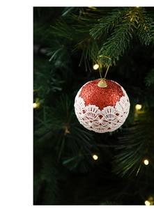 Macro shot of 8cm red Christmas ball with white lace lace and glitter on a festive tree