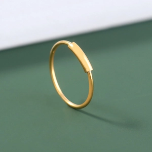 Macro shot of minimalist gold U-shaped nose ring with a polished small rectangular bar