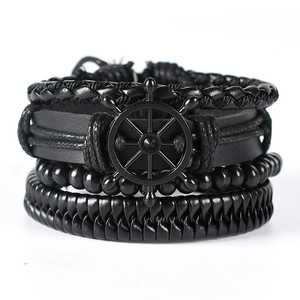 Close-up of black braided leather bracelets with a metallic helm charm for men