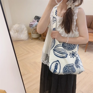 Détail d'un sac cabas en toile blanche avec motifs botaniques et baies peints en bleu