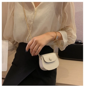Détail du mini sac selle en cuir blanc avec chaîne dorée porté par un mannequin chic
