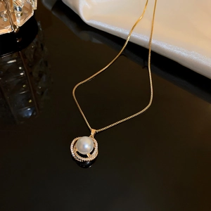 Detailed close-up of golden necklace pendant with large white pearl and zircon rings