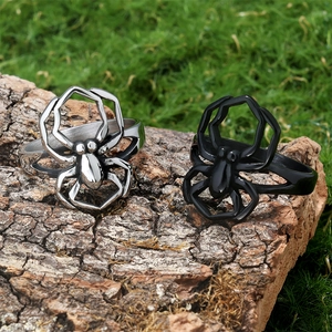 Detailed view of silver and black spider rings on natural bark with green moss background