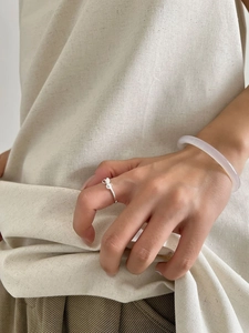 Detailed view of silver bow-shaped open ring and a translucent light purple jade bangle