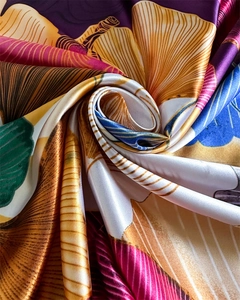 Macro view of silky satin scarf fabric with vibrant ginkgo leaf pattern and elegant sheen