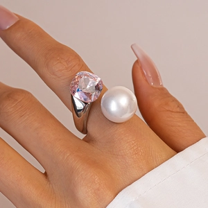 Macro detail of open ring with pink square zircon and glossy white pearl on model's hand