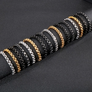 Three-color box chain bracelets in gold silver and black steel on a display stand
