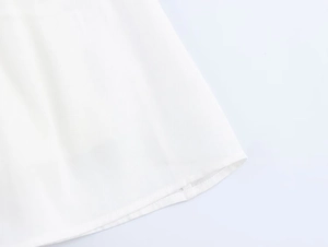 Close-up of white chiffon fabric texture and high-quality hem stitching details on a mini dress