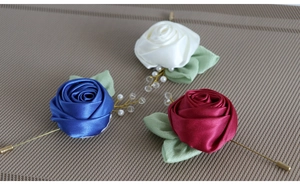 Detailed view of handmade satin rose boutonnieres with pearls and long golden metal pins