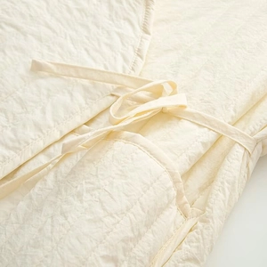 Detailed macro view of quilted cream fabric with textured tie closure on a casual vest