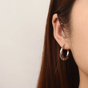 Close-up of silver twisted hoop earring in stainless steel worn by a model