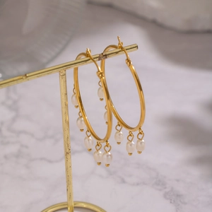 Elegant gold hoop earrings with natural freshwater pearl fringe on a metal stand