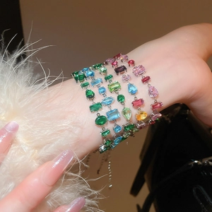 Close-up of luxury bracelets featuring colorful irregular zircon stones on a model's wrist
