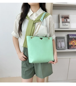 Detail of mint green woven tote bag featuring chain strap and triangle metal plaque