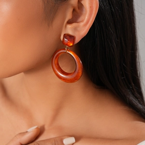 Gros plan d'une femme portant des boucles d'oreilles créoles ambre en résine