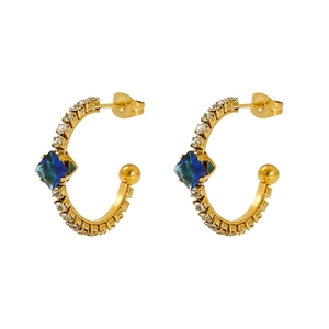 Detail of vintage gold C-shape earrings with blue square gem and crystal accents
