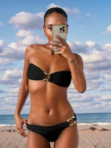 Detail of black bikini set featuring bold gold chain links on top and low-rise bottoms