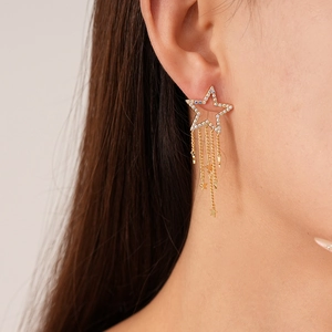 Close-up of elegant gold star tassel earrings with zircons on a female model