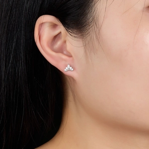 Macro shot of silver crown stud earrings with sparkling cubic zirconia on female ear