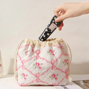Putting hand cream into a quilted drawstring bag with pink roses and bows