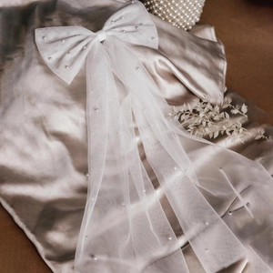 Elegant white mesh bow bridal veil with pearl accents on a champagne silk background