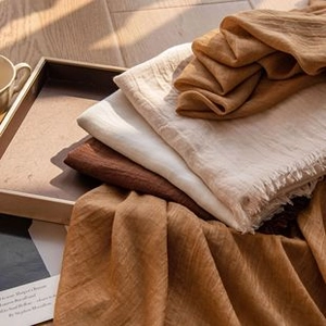 Cozy stacked cashmere-like plaid scarves in brown and beige tones on a wooden floor