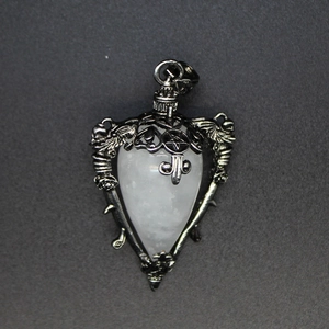 Detailed view of a heart-shaped white crystal pendant with gothic wing and skull metalwork
