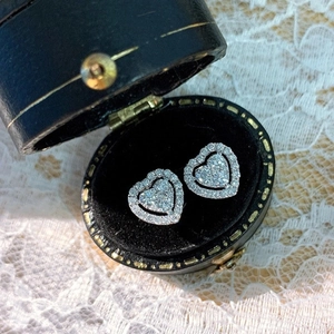 Close-up of heart-shaped pavé earrings with sparkling stones in a black velvet box