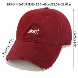 Detail of dark red baseball cap featuring white OKEY embroidery and distressed brim edge