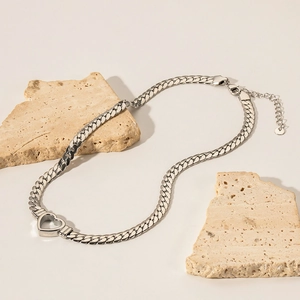 Polished silver heart pendant on a flat Cuban chain displayed on stone props