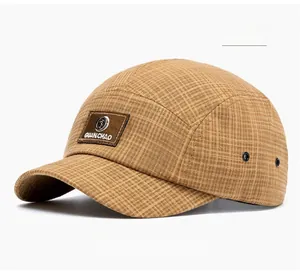 Close-up of brown plaid baseball cap featuring a leather logo patch and metal eyelets