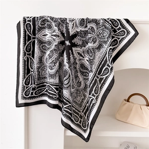 Detailed close-up of a black and white paisley silk scarf draped on a display rack