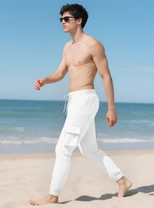 Close-up of white cargo pants with drawstring waist and side pockets on a sandy beach