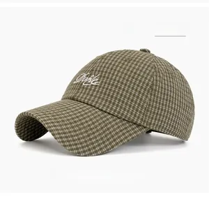 Close-up of military green plaid baseball cap featuring white cursive letter embroidery