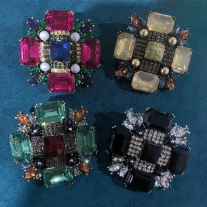 Detailed view of four vintage geometric rhinestone brooches in emerald and ruby tones
