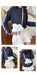 Detail of white plush cloud-shaped crossbody bag with cute feet and embroidered face