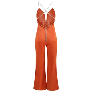 Detail of orange backless jumpsuit featuring crisscross rhinestone straps and satin fabric